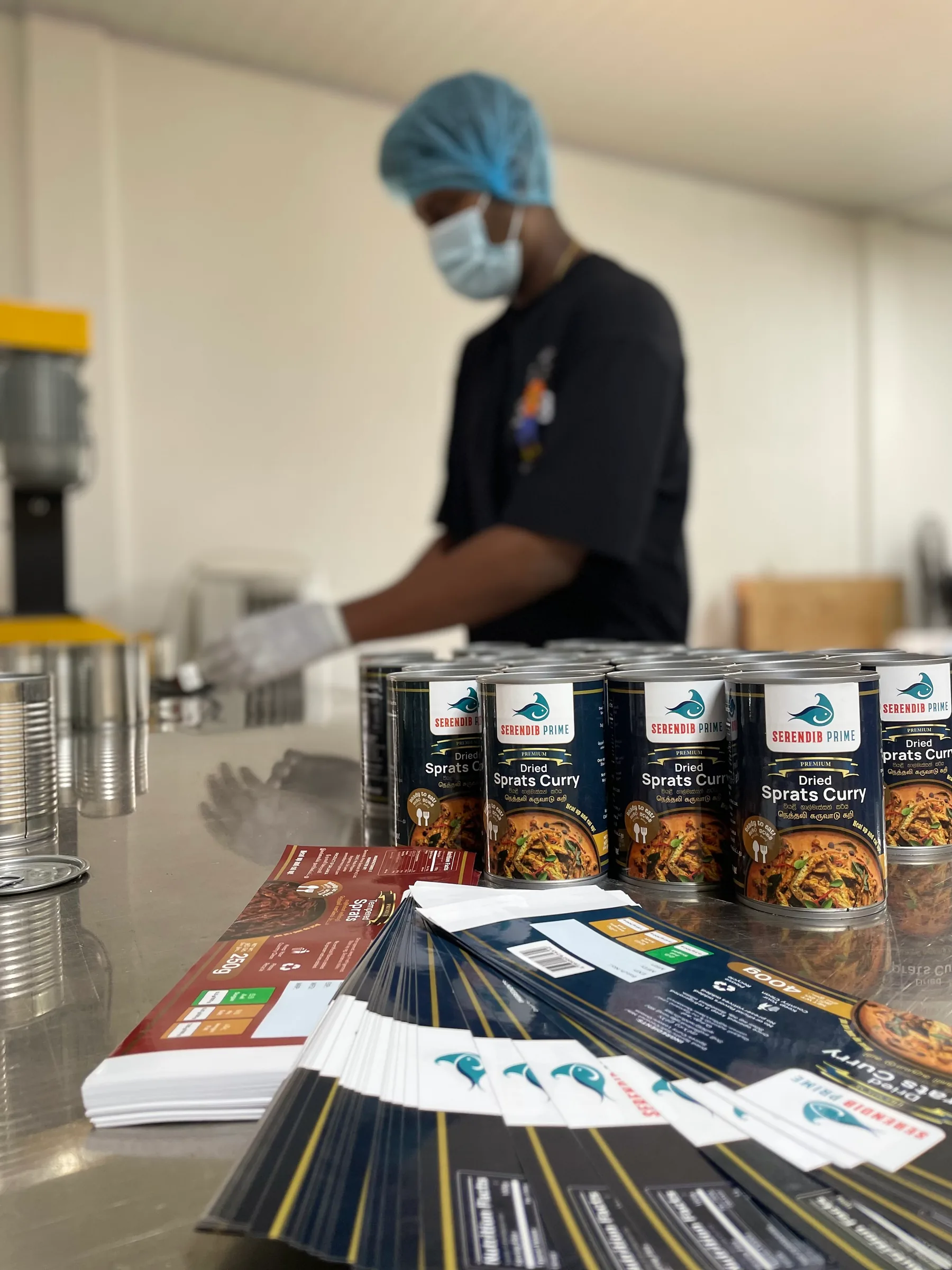 A Serendib Prime team member labelling tins of Dried Sprats Curry on the production line